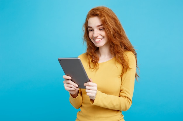 Menschen und Technologie-Konzept - Nahaufnahme Porträt junge schöne attraktive zärtliche Ingwer Redhair Mädchen glücklich lächelnd auf digitalen Tisch mit Wining etwas. Blauer Pastellhintergrund. Platz kopieren