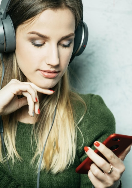 Menschen- und Technologiekonzept Glückliche Frau mit Kopfhörern, die Musik vom Smartphone hört