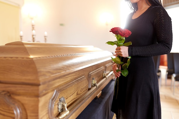Foto menschen und trauerndes konzept frau mit roten rosen und sarg bei der beerdigung in der kirche