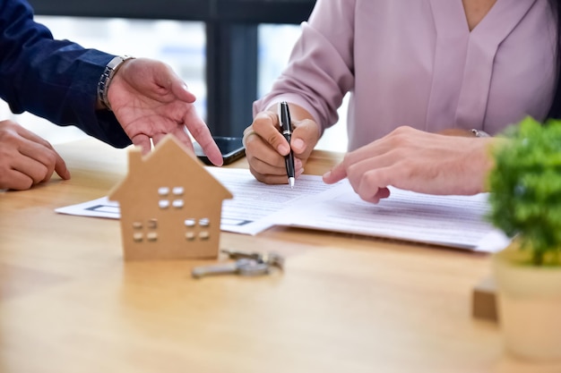 Menschen unterzeichnen Vertrag auf Dokument für Kauf von Haus und Investition