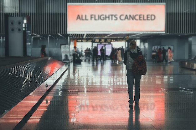 Menschen verlassen den flughafen. mädchen geht durch flughafenterminal. alle flüge werden gestrichen. abflug- und ankunftsverbot von flugzeugen aufgrund des ausbruchs von covid-19. probleme und krise in der luftfahrtindustrie.