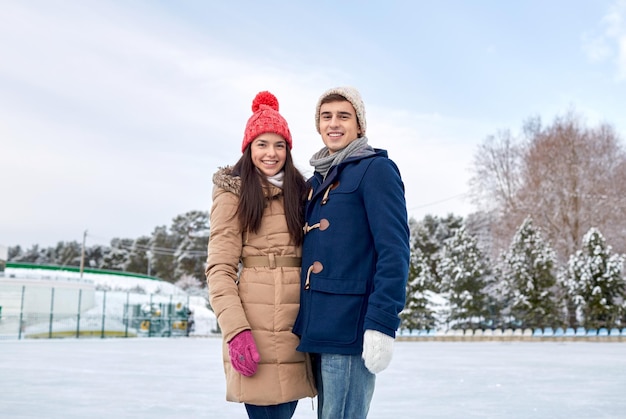 menschen, winter, freundschaft, liebe und freizeitkonzept - glückliches paar eislaufen auf der eisbahn im freien