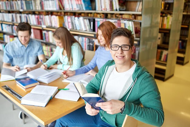 menschen, wissen, bildung und schulkonzept - gruppe glücklicher schüler, die bücher lesen und sich auf die prüfung in der bibliothek vorbereiten