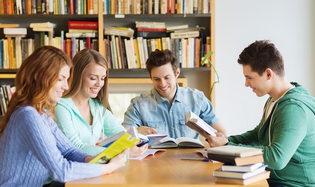 menschen, wissen, bildung und schulkonzept - gruppe glücklicher schüler, die bücher lesen und sich auf die prüfung in der bibliothek vorbereiten