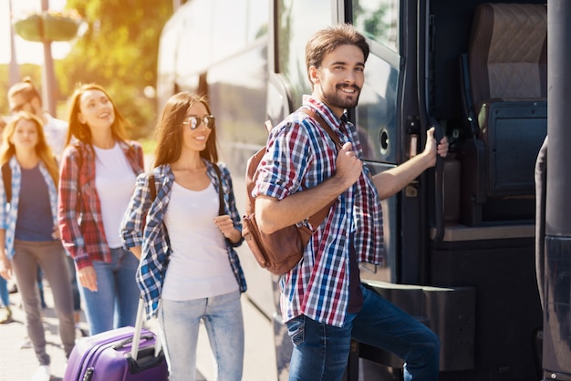 Menschenreihe Glückliche Touristen nehmen einen Bus.