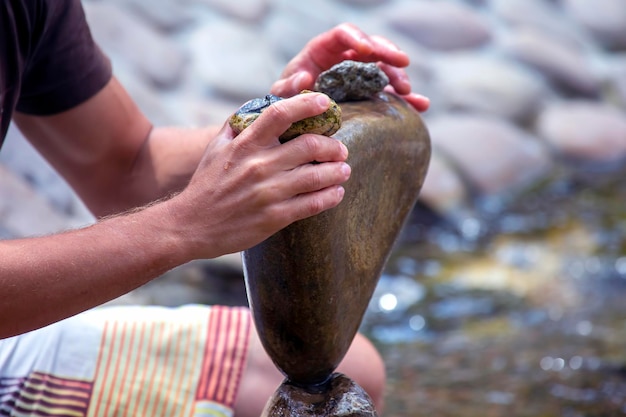 Menschliche Hände bauen einen Steinhaufen auf dem Wasser. Gleichgewicht und Meditation