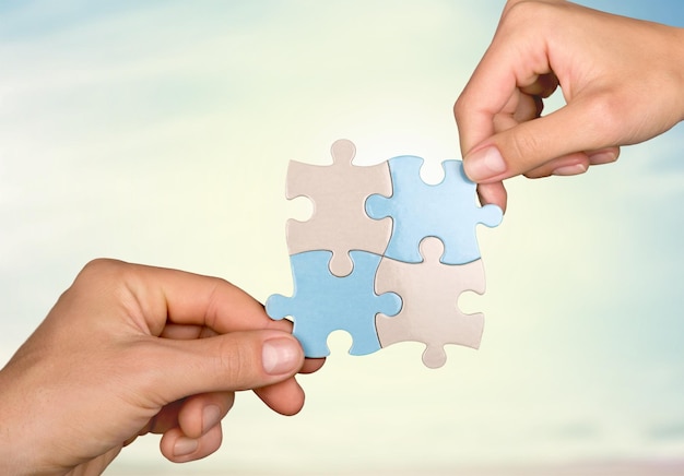 Menschliche Hände, die Puzzleteile im Hintergrund verbinden