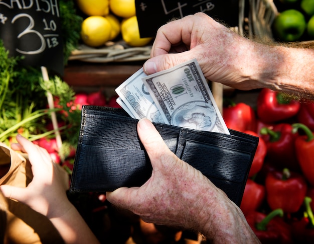 Menschliche Hand, die das Geld hält und Waren ausgibt