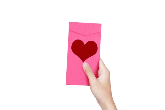 Menschliche Hand, die einen rosa Umschlag mit Herzform lokalisiert über weißer Wand hält