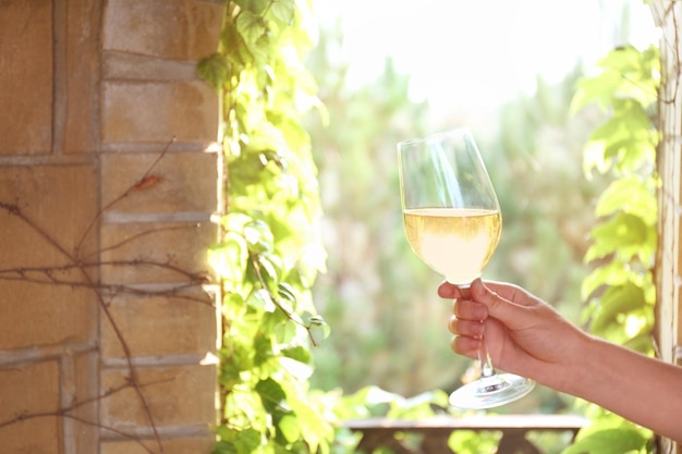 Menschliche Hand, die Glas mit Wein auf Steinbogenhintergrund hält