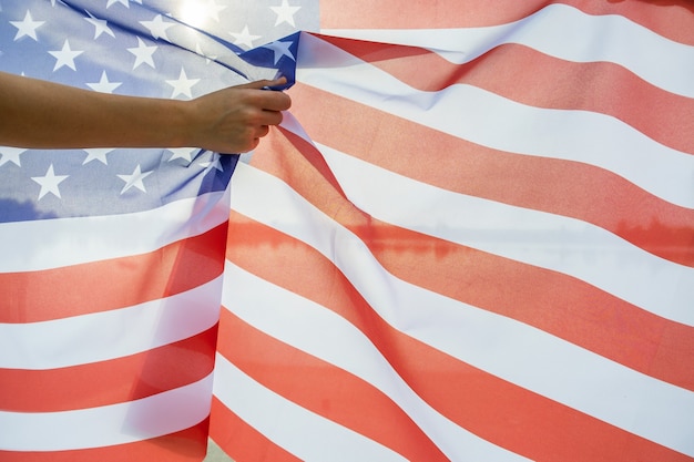 Menschliche Hand, die USA-Nationalflagge hält.