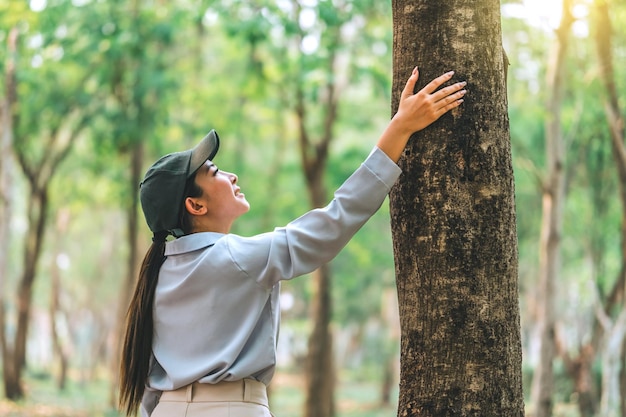 Menschliche Hand umarmt und berührt einen Baum im Wald. Menschen schützen sich vor Abholzung und Umweltverschmutzung oder dem Klimawandel. Konzept zur Liebe zur Natur und Baumumweltökologie und Konzept zum Tag der Erde