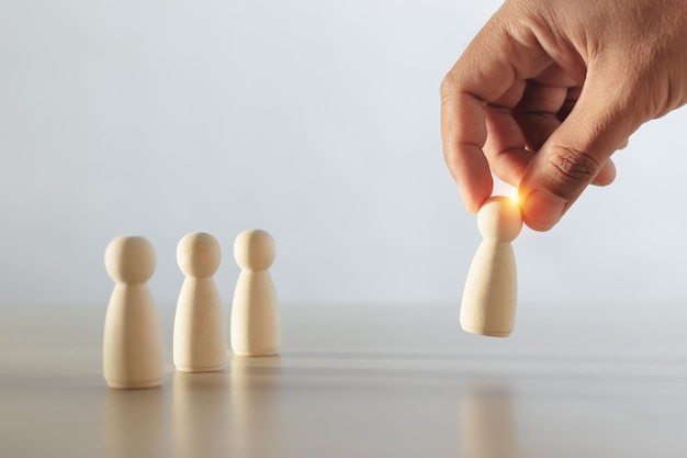 Menschliche Holzfiguren wurden als Leiter der Teamarbeit gewählt. Männerhände sind ausgewählte Holzpuppen, um Strategien für die Ernennung von Führern zu entwickeln. Führung des Teamwork-Konzepts.