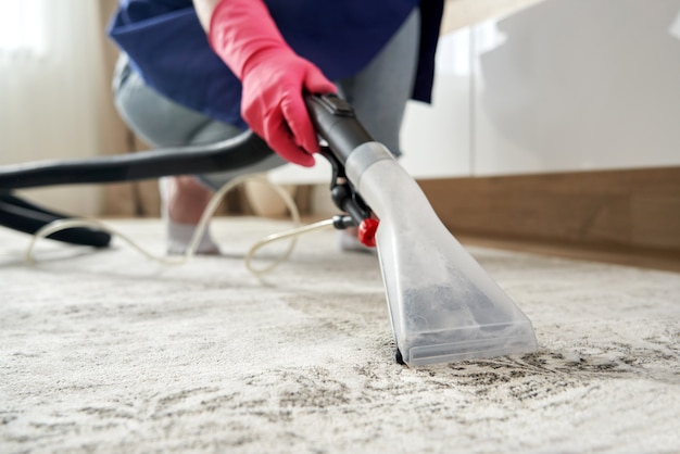 Menschlicher Reinigungsteppich im Wohnzimmer mit Staubsauger zu Hause