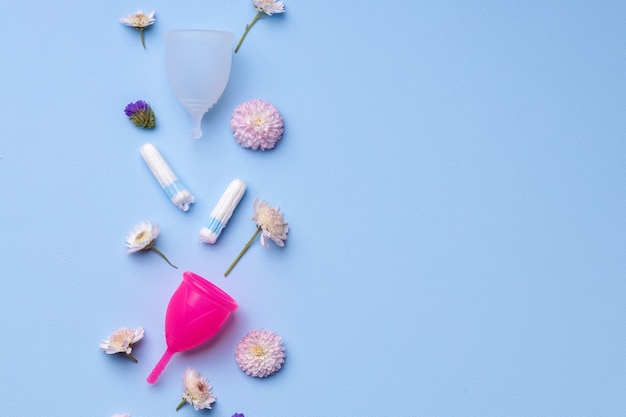 Menstruationshygieneprodukte mit Blumen auf blauer Oberfläche