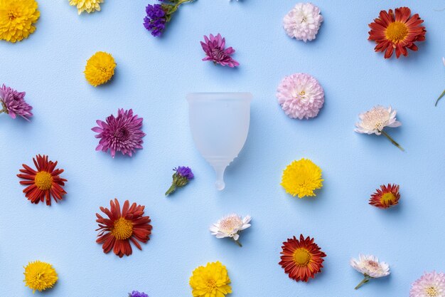 Menstruationstasse auf Blumenmusterhintergrund-Draufsicht, Kopienraum