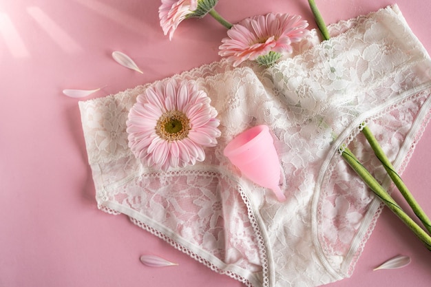 Menstruationstasse aus Silikon Frauengesundheit und alternative Hygiene Tasse mit Blume auf rosa Hintergrund Zero Waste Alternativen