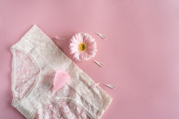 Menstruationstasse aus Silikon Frauengesundheit und alternative Hygiene Tasse mit Blume auf rosa Hintergrund Zero Waste Alternativen