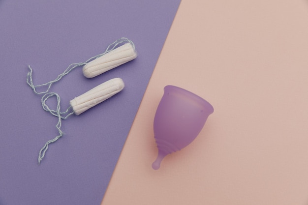 Menstruationstasse und Tampons auf einem bunten Hintergrund-Draufsicht-Konzept der Frauenhygiene und des Gesundheitswesens