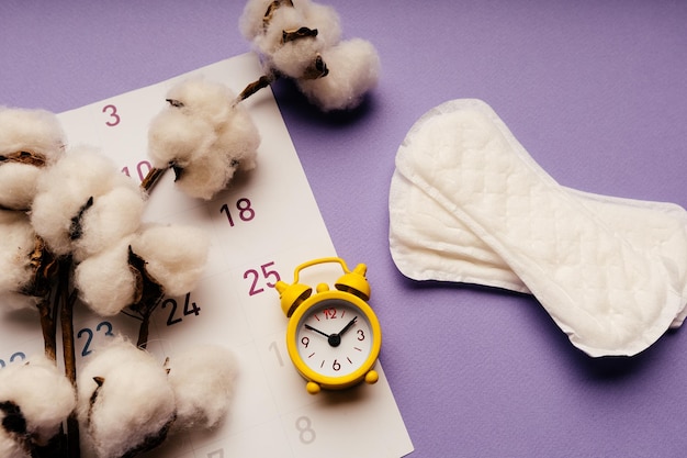 Menstruationszykluskonzept für Frauen Damenbinde und Wecker im Kalender