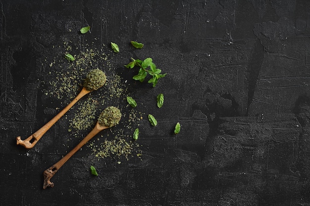 menta en cuchara de madera aislada en fondo negro hierbas y especias en fondo de madera