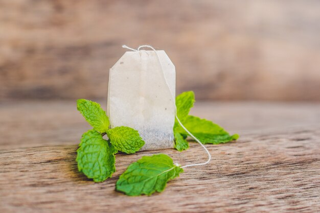 Menta fresca y bolsita de té en mesa de madera