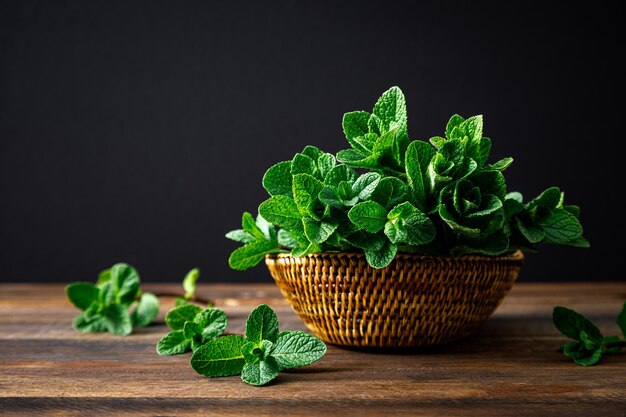 Menta fresca en una canasta sobre fondo oscuro