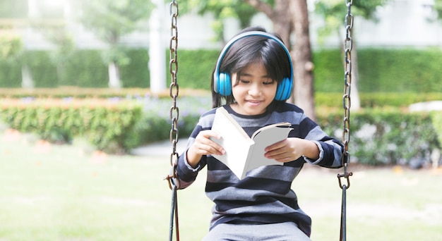 Mentalidad introvertida en la generación digital de niños asiáticos felices con música en los auriculares y quedarse solos en el parque