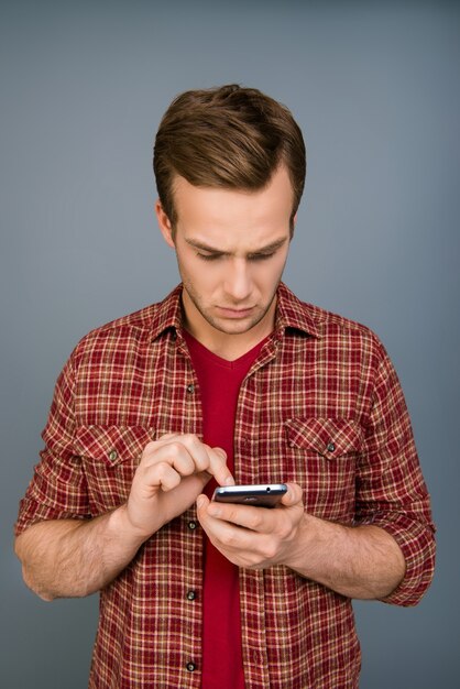 Mente seria joven escribiendo mensaje en smartphone