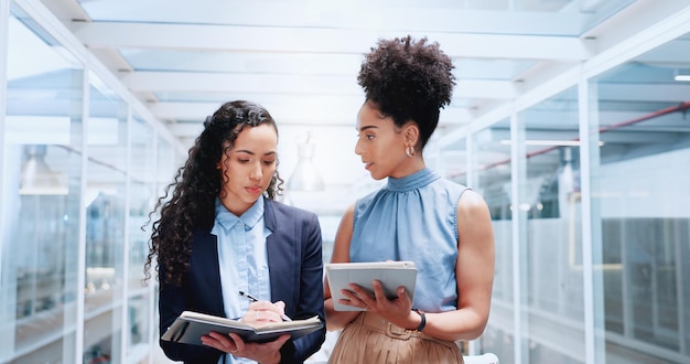 Mentorendiskussion und Geschäftsfrauen, die am Büroarbeitsplatz spazieren gehen Führungscoaching und eine Gruppe von Personen oder Mitarbeitern im Flur sprechen über Planung oder Brainstorming-Projekt mit Tablet und Büchern