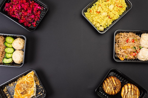 Foto menú de catering de alimentos saludables en cajas de almuerzo paquetes de carne y vegetales aislados sobre fondo negro