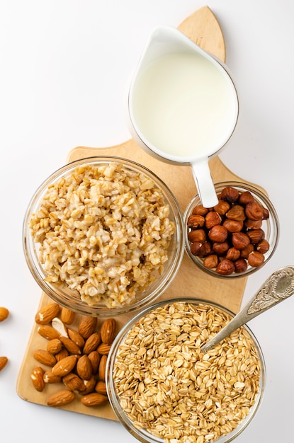 Menú de comida dietética para el desayuno con un tazón de avena con nueces y tarro de leche sobre tabla de madera