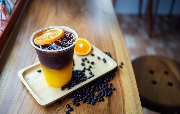 Menu de bebidas de café gelado Orange Americano com frutas frescas de laranja misturadas em um copo de plástico