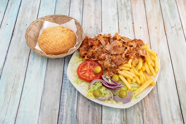 Menu de prato de kebab turco de carne de frango assada com salada de alface tomate azeitonas verdes e cebola roxa guarnecido com batatas fritas e pão pita grelhado