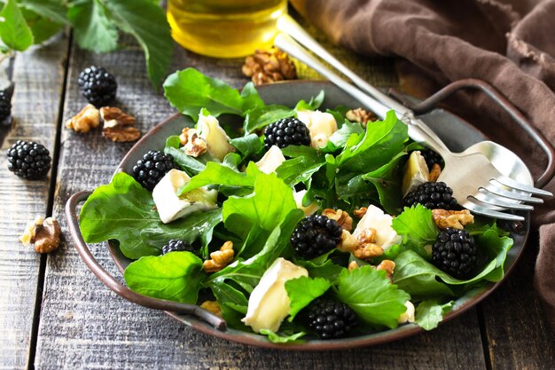 Menú dietético Comida vegana Ensalada saludable con rúcula, queso brie, nueces y aderezo de vinagreta