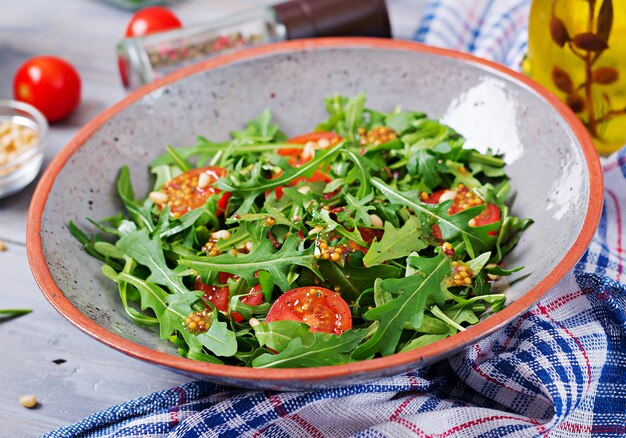 Menu dietético. cozinha vegana. salada saudável com rúcula, tomate e pinhões.