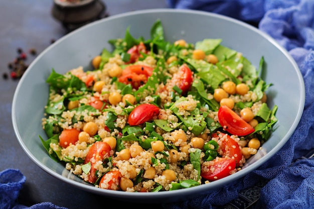 Menú dietético Ensalada vegana saludable de verduras frescas - tomates, garbanzos, espinacas y quinua en un tazón.