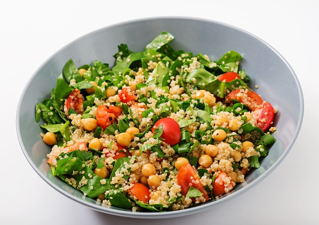 Menú dietético Ensalada vegana saludable de verduras frescas - tomates, garbanzos, espinacas y quinua en un tazón.