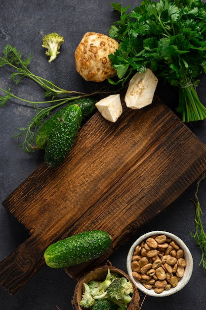 Menú de fondo de alimentos. Tabla de cortar de madera rústica con ingredientes para cocinar comida vegana en la vista superior de fondo oscuro