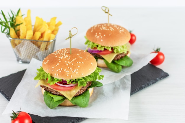 Menú de hamburguesas de comida rápida papas fritas en tablero de pizarra en mesa blanca