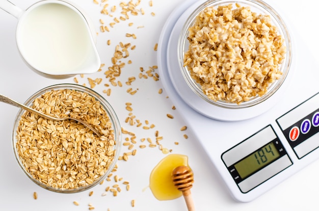 Menú de nutrición adecuado para el desayuno con gachas de avena en balanzas de cocina digitales, leche y miel