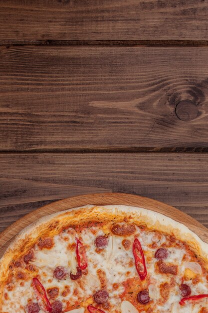 Foto menú de restaurante de pizza: deliciosa pizza picante con salchichas y ají. pizza en mesa de madera rústica con ingredientes