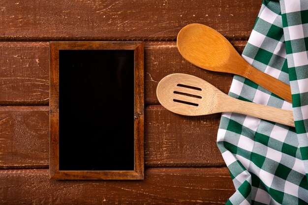 Menú del restaurante. Vista superior del menú de pizarra en el escritorio de madera rústica con cucharas y servilleta verde.