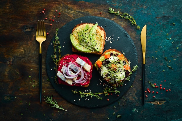 Menú sándwich ciabatta aguacate pescado hummus y microgreen Desayuno En un plato de piedra negra