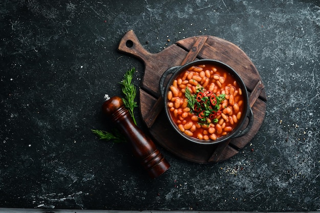 Menú vegetariano Frijoles guisados en salsa de tomate con perejil y chile En un tazón negro Vista superior Espacio libre para su texto