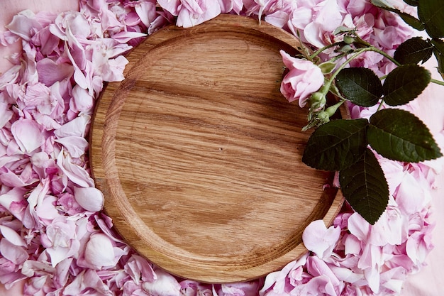 Menü oder Einladung Mockup Holzplatte Podium Einladung Hochzeit Muttertagskarte Mockup zwischen rosa Tee Rosenblättern Platz für Text Ansicht von oben