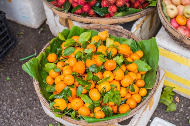 Mercado de agricultores asiáticos vendiendo mandarina fresca en Hoi An, Vietnam. Colores naranja y verde.