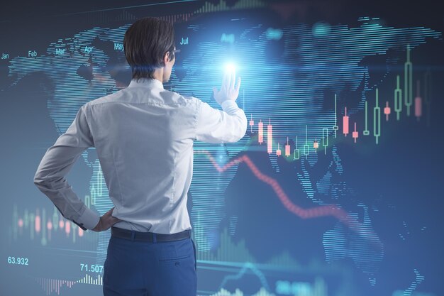 Mercado de ações e conceito de negociação com vista traseira do homem tocando a tela de parede digital com mapa-múndi e castiçal e diagrama de gráfico financeiro