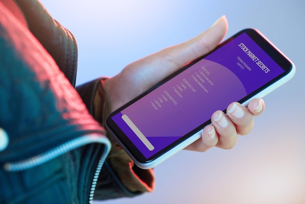 Mercado de ações por telefone e informações com a mão de uma pessoa no estúdio em um fundo de néon para educação Dados móveis e negociação com um comerciante adulto lendo um tutorial ou closeup de instruções