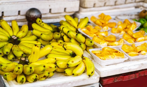 Mercado de agricultor de rua asiático vendendo frutas frescas em hoi an, vietnã. bananas e durian. cor amarela e laranja.